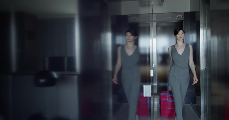 Woman pulls a suitcase down a narrow hallway