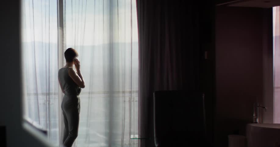 A woman talks on her phone behind the drapes
