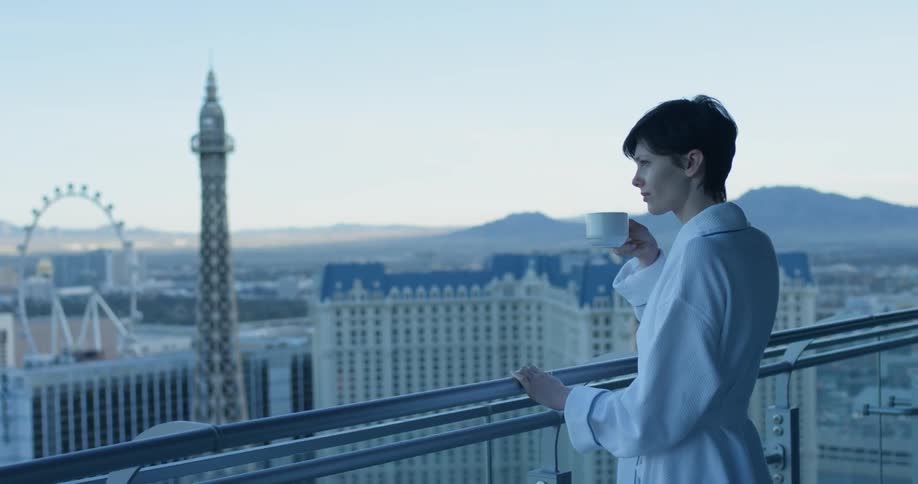A woman looks over her balcony towards the city