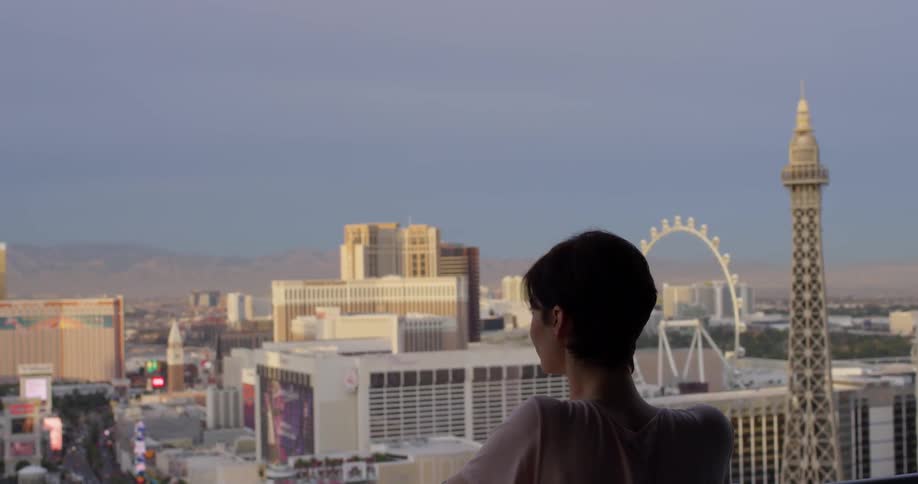 Woman looks out at the city under a blue sky