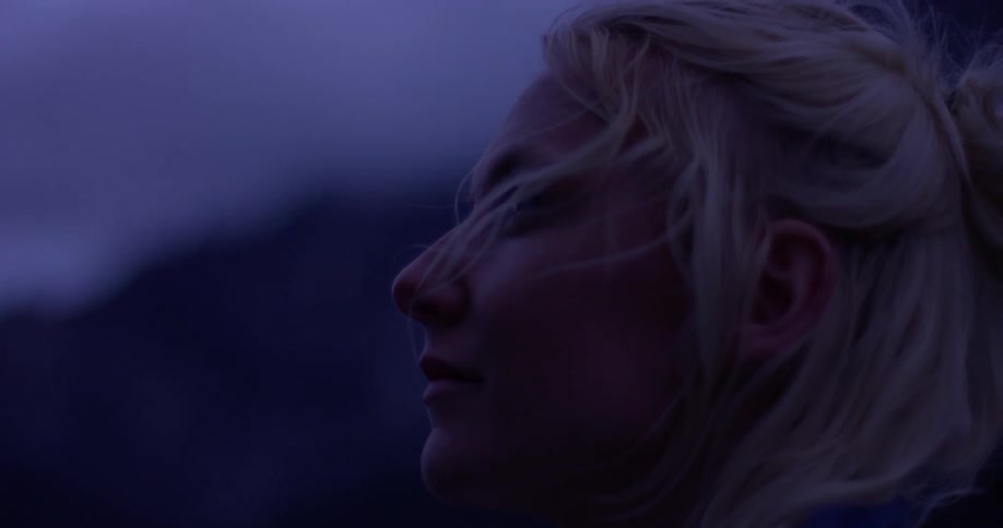 Woman stands outside looking out on a cloudy evening