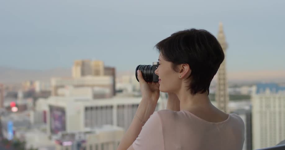 A woman takes a photograph of las vegas from a hotel balcony