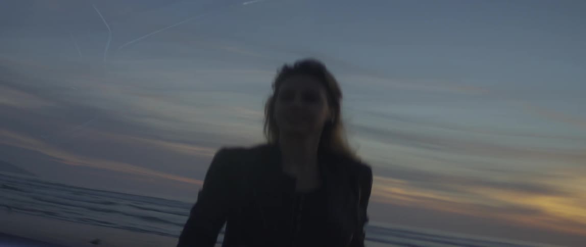 Woman takes a picture of the ocean at sunset