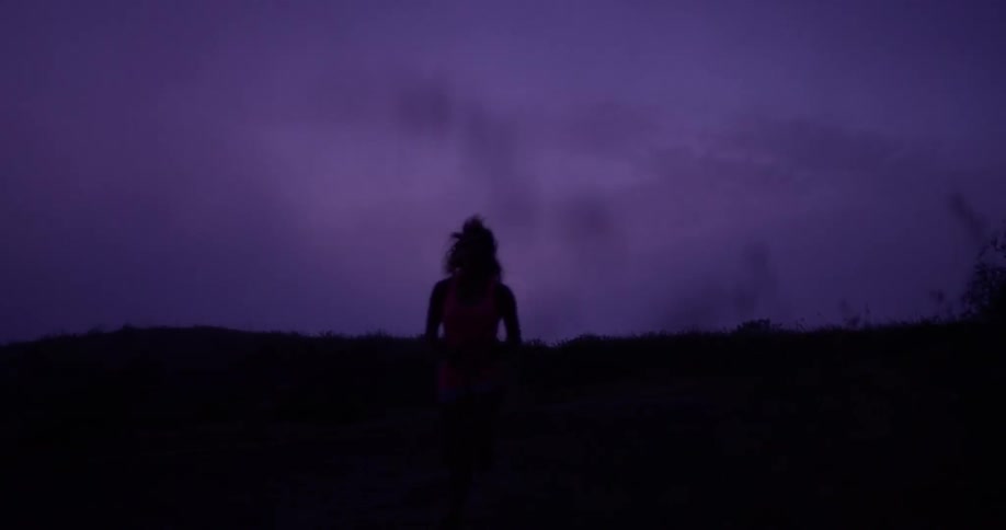 A woman runs at dawn on the dark field
