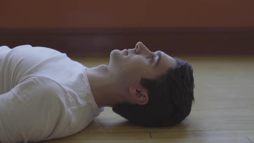 A man lies on a wood floor