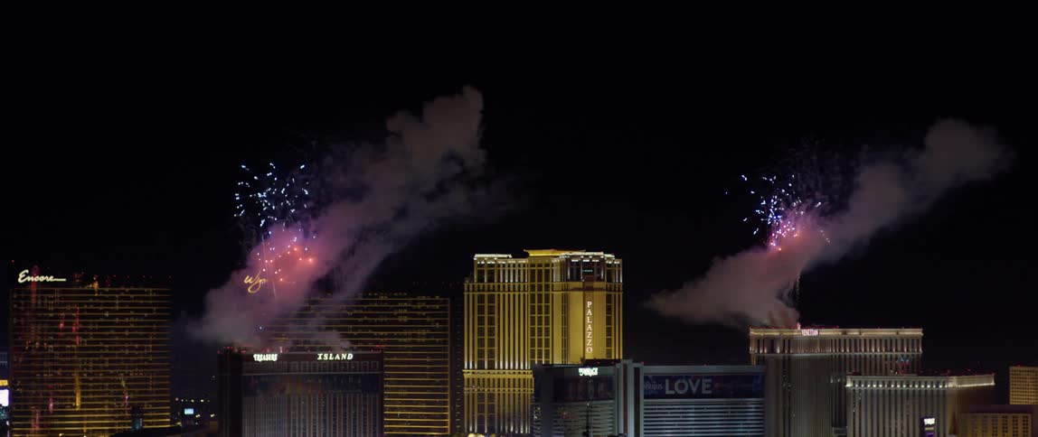Fireworks shoot off from the top of buildings in the city at night