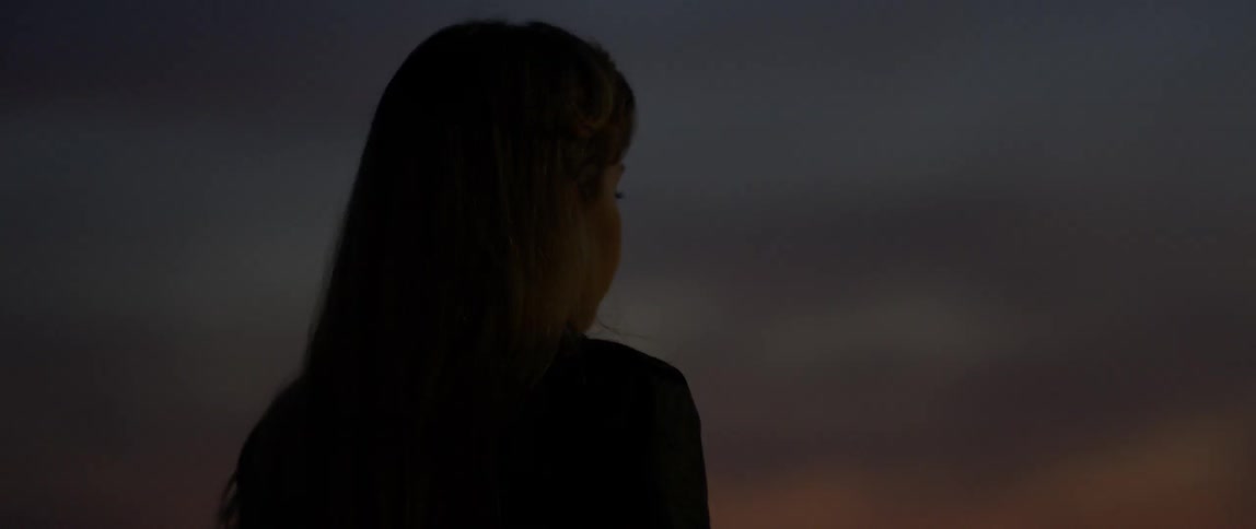 A woman stands outside at dusk