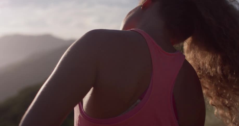 A woman standing outside stretches her neck in the sunshine