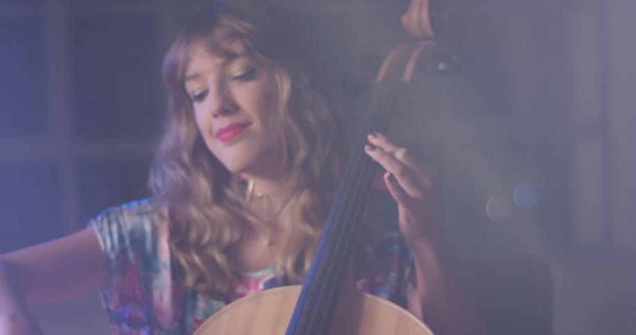 Woman is playing the cello indoor at night