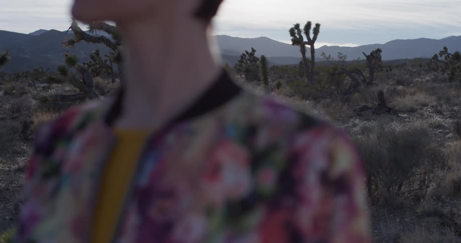 Woman stands in the desert with the sun shining down