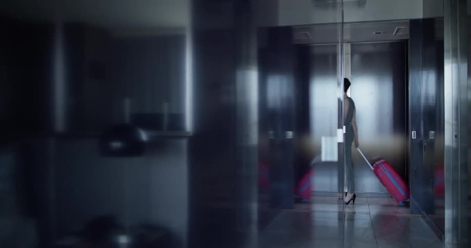 A woman rolls a suitcase in a hotel room