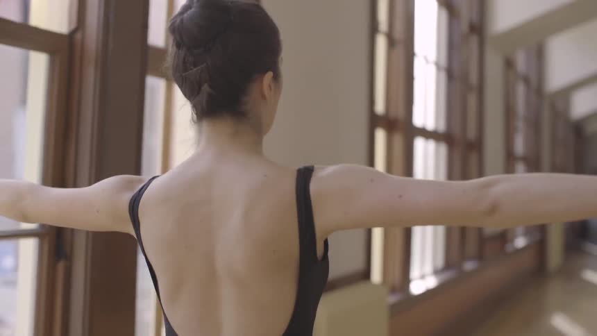 Woman waves her arms and walks down a sunny hallway