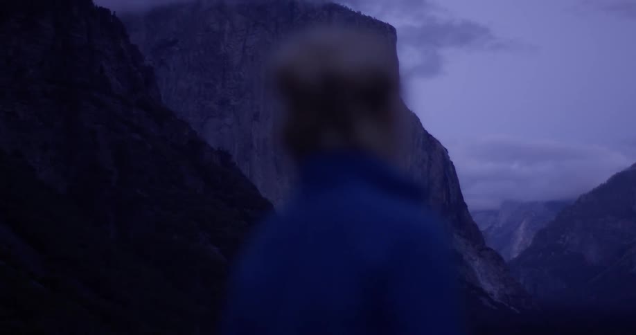 A woman stands outside near the mountains