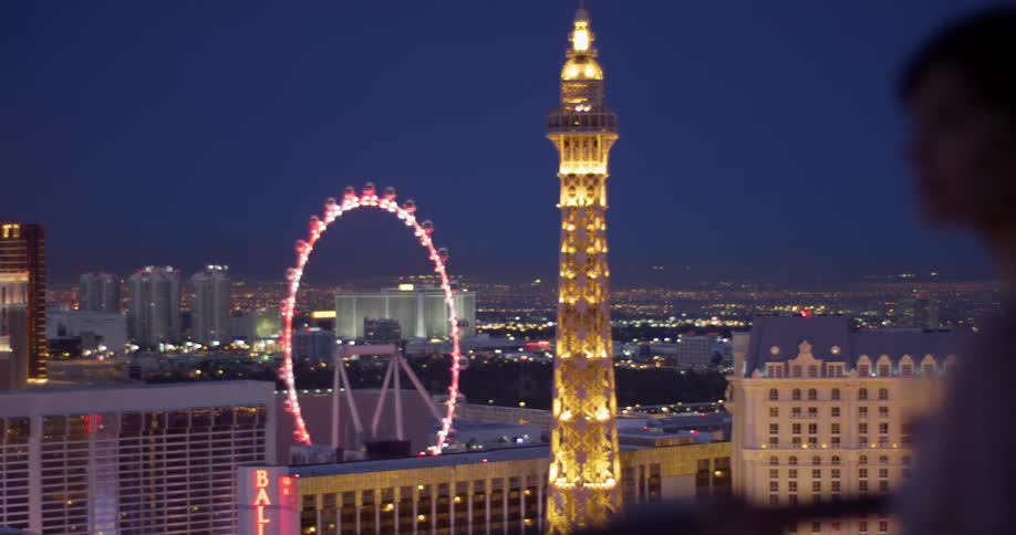 Woman looks out at a lit up tower and ferris wheel at night