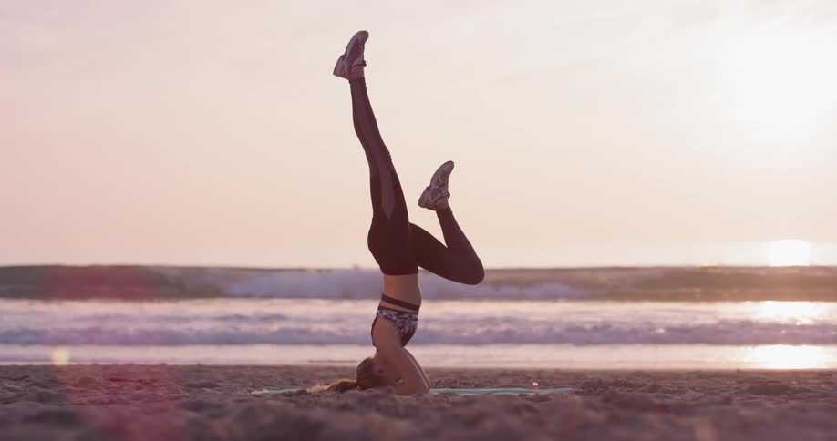 Woman does yoga on the beach on a sunny day