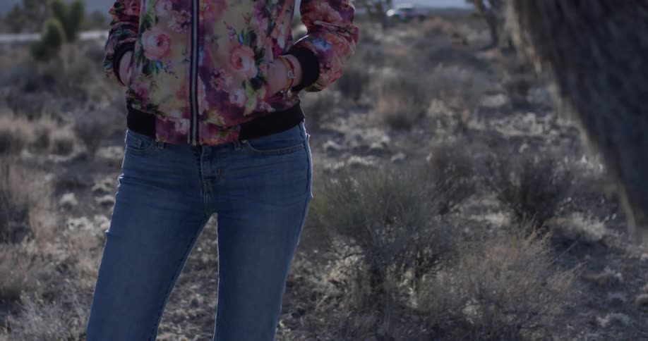 A woman stands alone in a desert