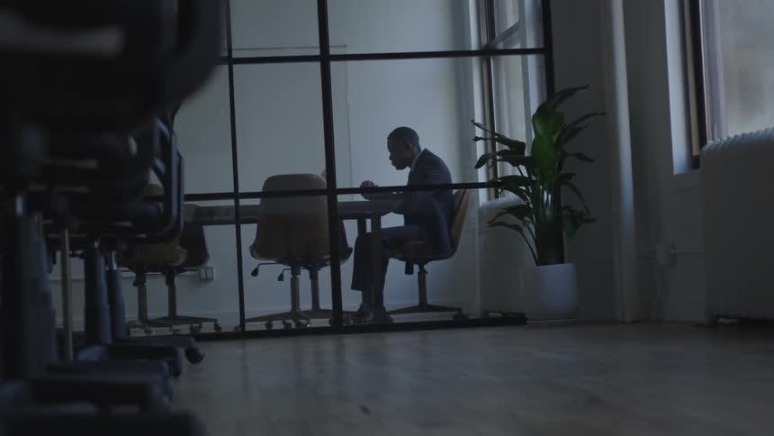 The man is sitting at the desk in the office