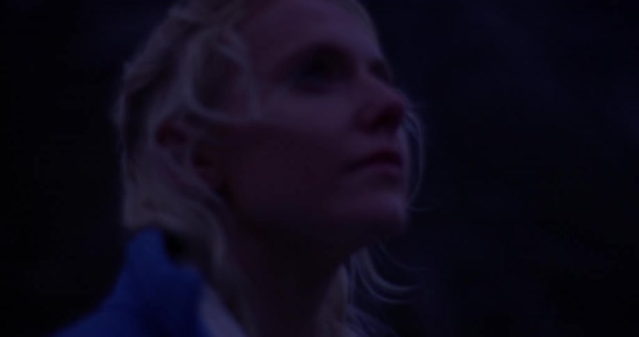 A woman looks up at the mountains