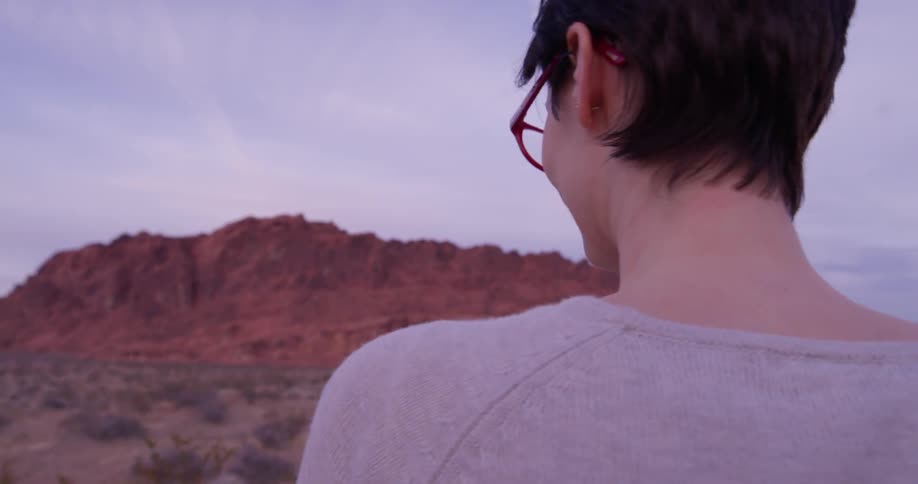 A woman walks in the desert on a cloudy day