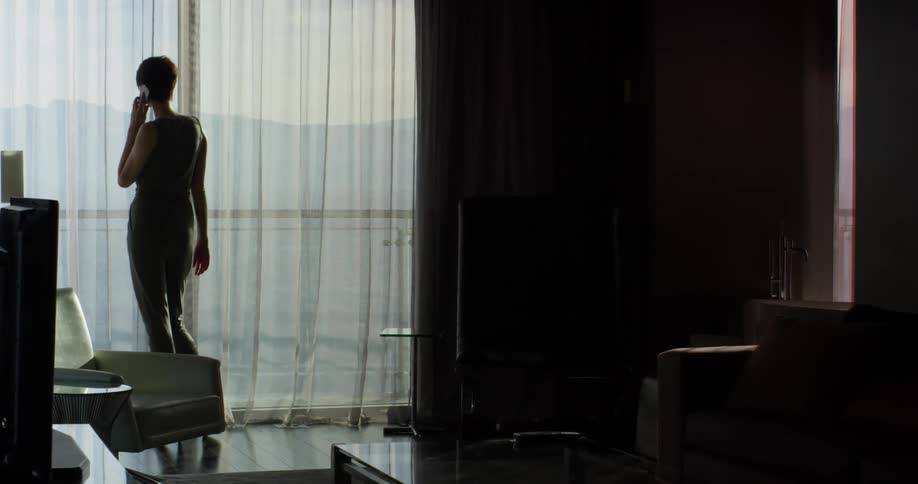A woman talks on a phone in a hotel room
