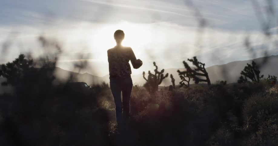 Woman walks in the field under the bright sun