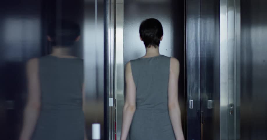 Woman walks down a narrow hallway pulling a suitcase