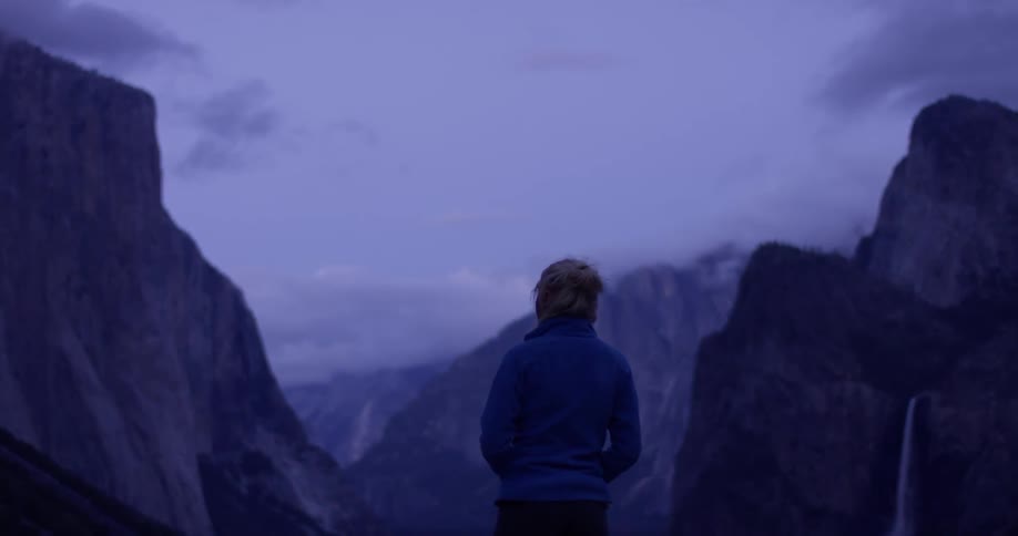 Woman stands outside on a cloudy evening looking at mountains