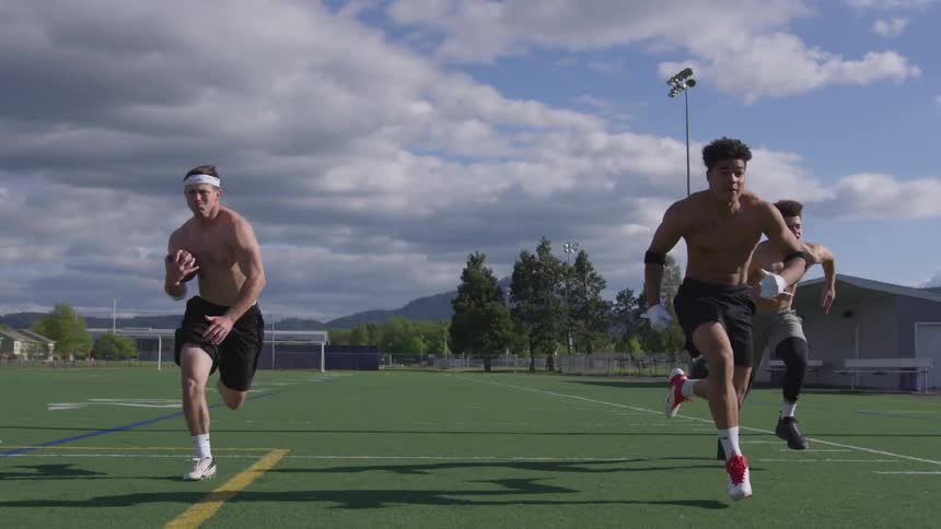 Four boys sprint on a football field