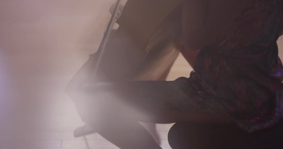 A woman is playing a cello inside in daylight