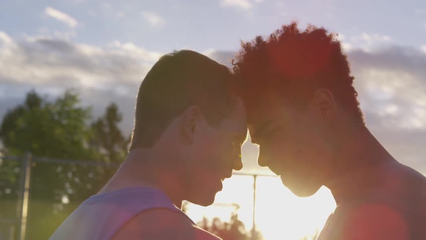 Two boys stand head to head and trash talk on an athletic field