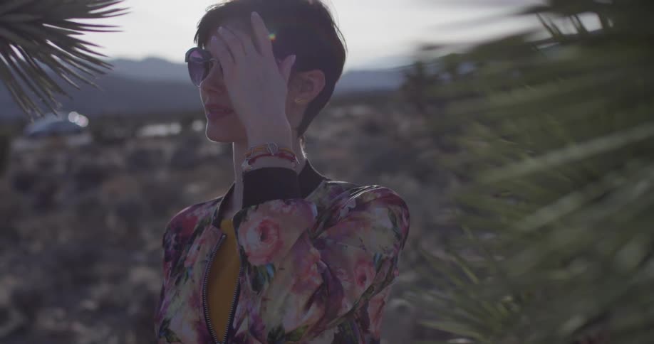 A woman wears sunglasses in a desert