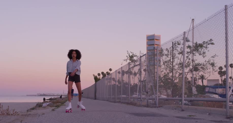A woman skates on a sidewalk at sunset