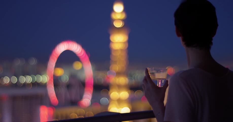 A woman has a drink on her balcony at dawn