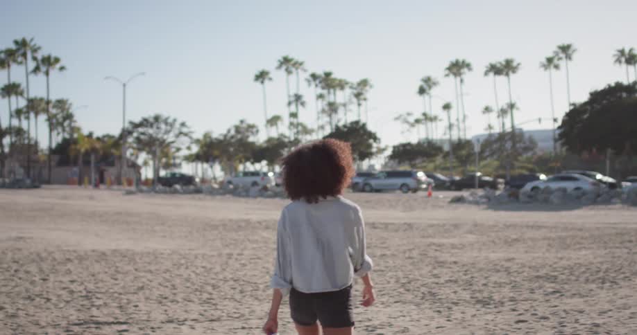 Woman carries roller skates on a large sandy beach