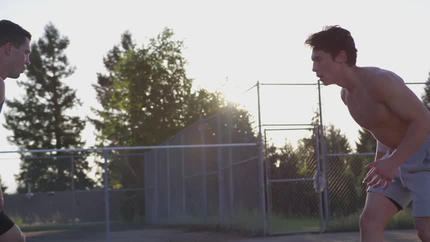 Four men play basketball on a sunny day