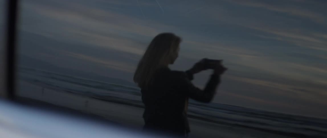 Woman standing on the beach turns around and takes a picture