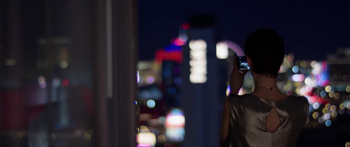 A woman takes a picture of las vegas from a hotel balcony