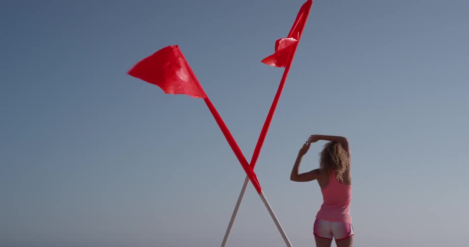 Woman stretches her arms near two waving red flags