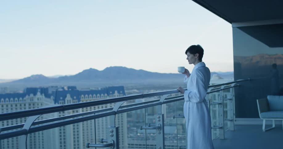 A woman has a drink in her robe outside