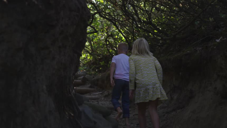 Two kids walk in the woods on a sunny day