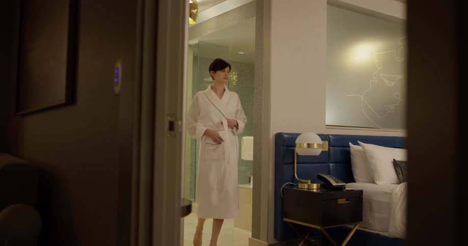 Woman walks through a bathroom wearing a robe