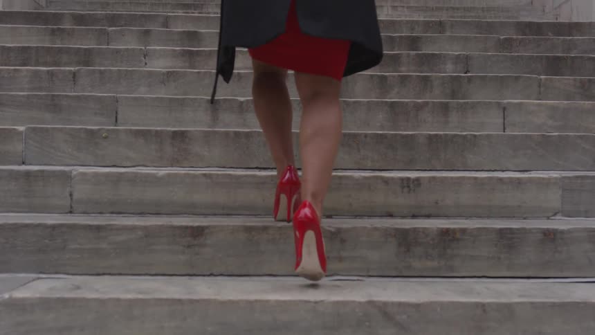 A woman climbs concrete steps in a city