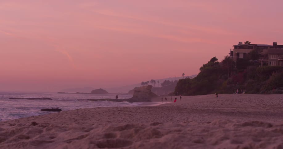 People walk on the beach at sunset