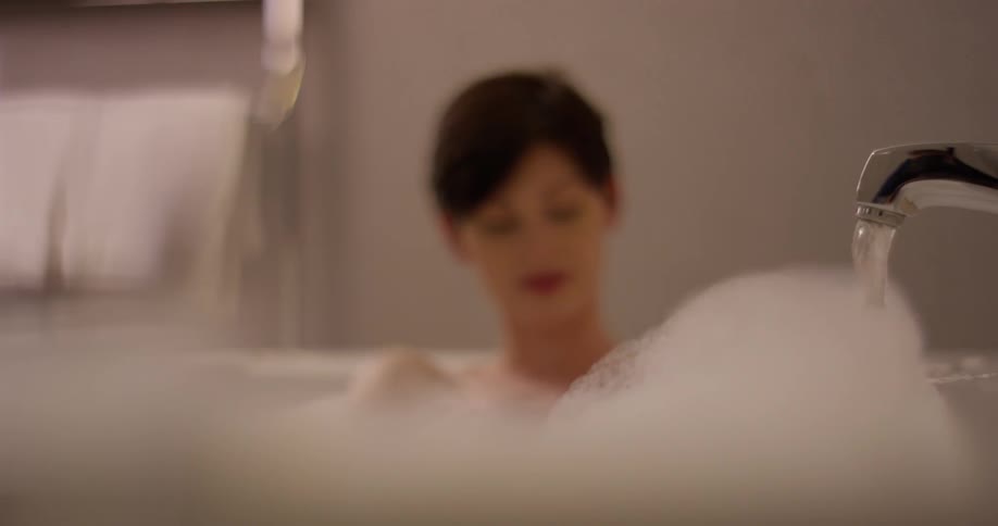 A woman moves the bubbles around in her bath