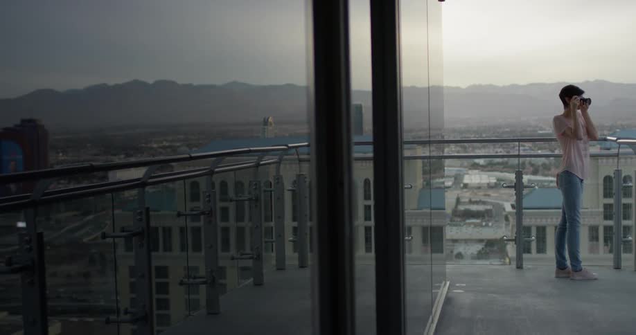 A woman takes a picture on a hotel balcony