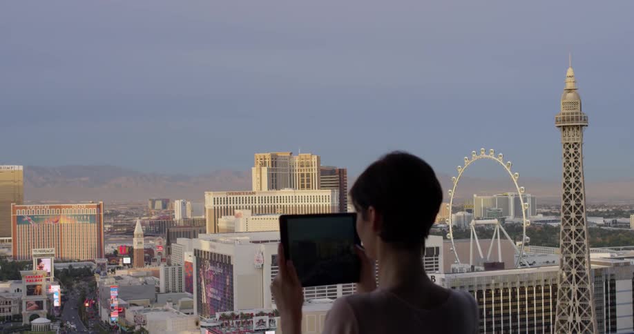 A woman uses a tablet to take a picture of las vegas
