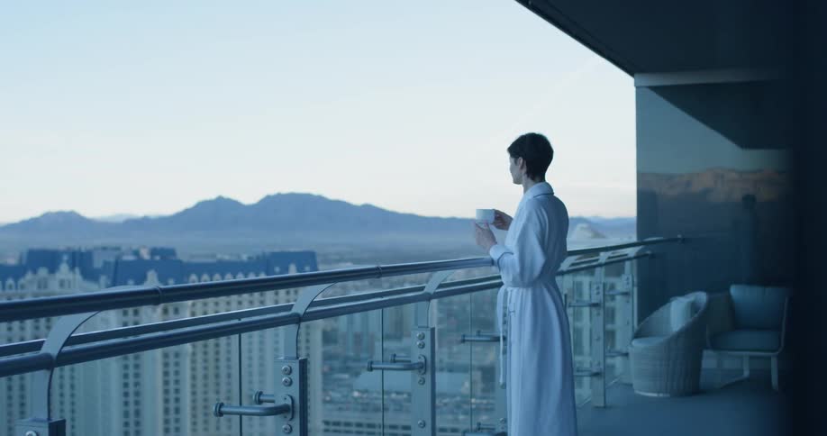 The woman walks out on her large balcony overlooking the city