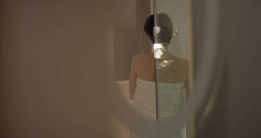 A woman puts on a towel in the bathroom