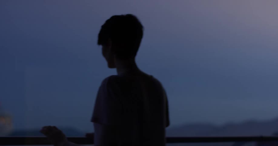 A woman stands on a hotel balcony at sunset