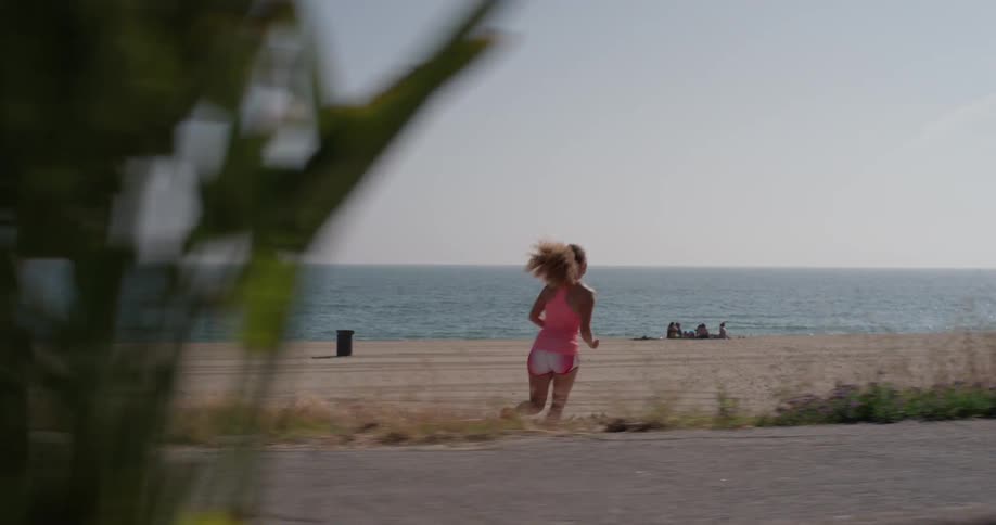 A woman jogs onto the beach